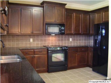 Kitchen tile floors and backsplash, granite counter tops, pantry and black appliances.