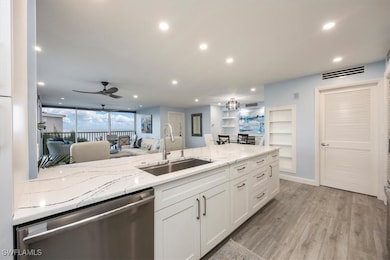 Kitchen featuring stainless steel dishwasher, white cabinetry, recessed lighting, light stone countertops, and light wood-type flooring