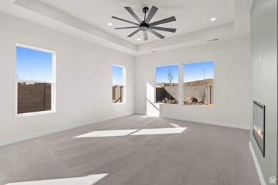 Unfurnished room with light carpet, plenty of natural light, a tray ceiling, recessed lighting, and ceiling fan