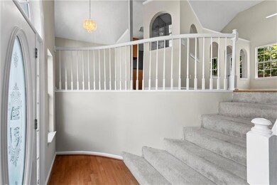 Entryway with vaulted ceiling, wood finished floors, stairway, and baseboards