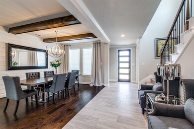 The oversized dining room features a ship-lap accent wall, wooden accent beams on the ceiling and a contemporary chandelier
