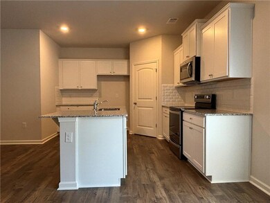 Kitchen featuring stainless steel appliances, stone counters, decorative backsplash, white cabinets, and recessed lighting