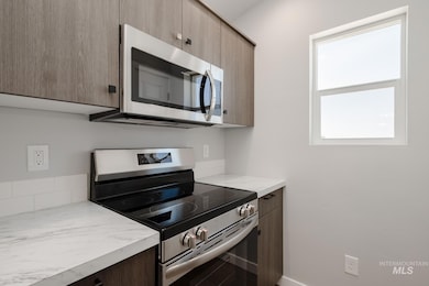 Kitchen with appliances with stainless steel finishes, light stone counters, and modern cabinets