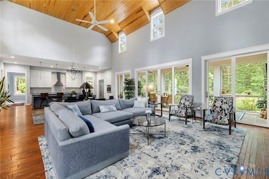Living area featuring wood-type flooring, healthy amount of natural light, wooden ceiling, high vaulted ceiling, and ceiling fan