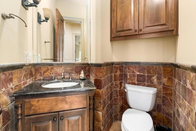 Half bathroom with vanity, wainscoting, and tile 