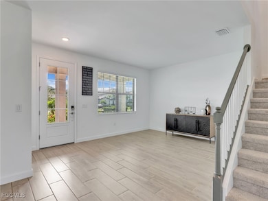 Foyer entrance with stairway, wood finish tile floors, and recessed lighting