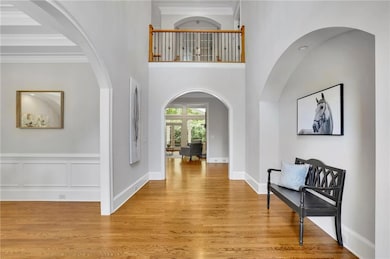 Entryway with ornamental molding, light wood finished floors, and arched walkways