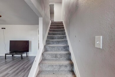 Staircase featuring a textured wall, baseboards, a