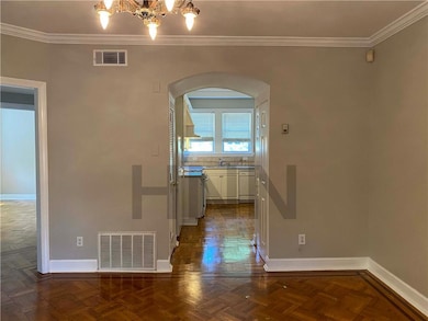 Unfurnished dining area featuring arched walkways, crown molding, and a chandelier