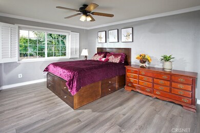 Primary suite with sparkling windows, new plantation shutters, lighted ceiling fan, new mirrored closet doors and new wood floors.