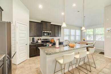 Stylish kitchen and dining combo features modern finishes, pendant lighting over the sleek island with bar seating.