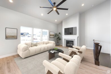 Living area featuring recessed lighting, light wood-type flooring, a fireplace, high vaulted ceiling, and a ceiling fan