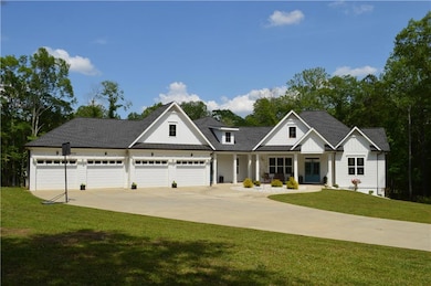Modern farmhouse with a front yard, driveway, a porch, roof with shingles, and board and batten siding