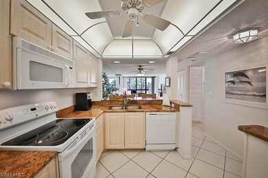 Kitchen with white appliances, light tile patterned flooring, and a peninsula