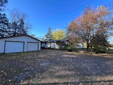 View of front of property featuring a garage, driveway, and an outdoor structure