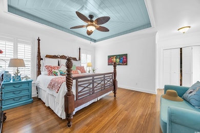 Bedroom with wood ceiling, a tray ceiling, wood finished floors, a ceiling fan, and a closet
