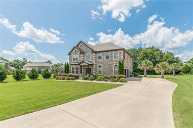 View of front facade featuring driveway, stone siding, and a front lawn