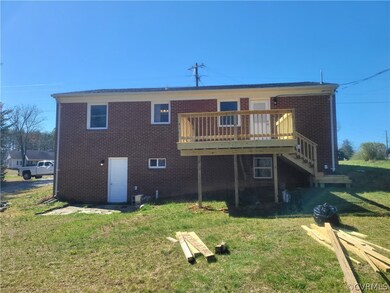 Back of property featuring a wooden deck and a yar