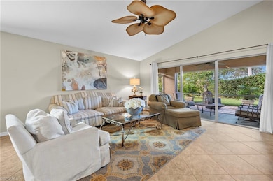 Living room featuring ceiling fan, light tile patterned flooring, and lofted ceiling