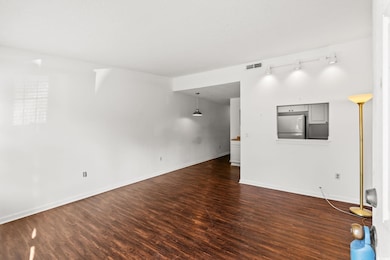 Unfurnished living room featuring dark wood-style floors and rail lighting