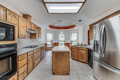 Kitchen featuring a center island, sink, black appliances, a raised ceiling, and pendant lighting