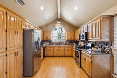 Features of the kitchen include granite countertops, glass tile backsplash, gas range and laminate flooring.