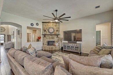 The large living room includes a stone fireplace and durable engineered hardwood flooring.