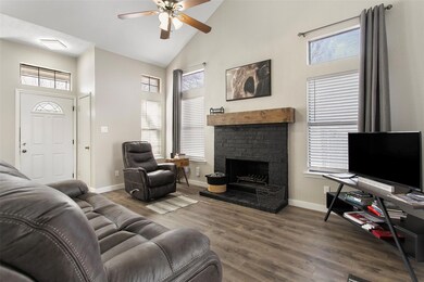 Living room with dark wood-type flooring, ceiling fan, a fireplace, and high vaulted ceiling