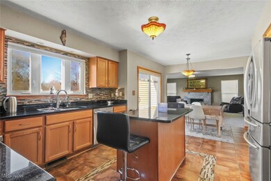 Kitchen featuring a fireplace, brown cabinetry, backsplash, appliances with stainless steel finishes, and decorative light fixtures