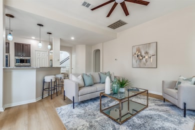 Living room with light wood-type flooring, a ceiling fan, and recessed lighting