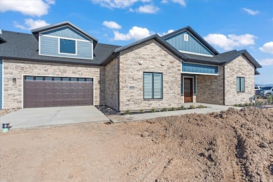 View of front of property with board and batten siding, driveway, stone siding, and a shingled roof
