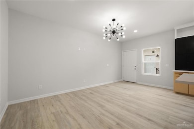 Unfurnished living room featuring a chandelier, recessed lighting, light wood-type flooring, and baseboards