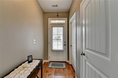 Doorway with baseboards, visible vents, and wood f