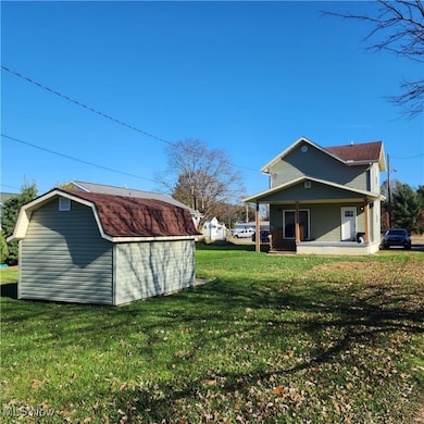 Back of house featuring a storage shed, a porch, a yard, and a gambrel roof