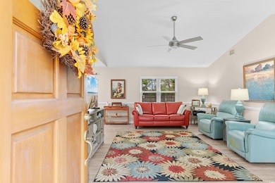 Living area featuring vaulted ceiling, light wood-style floors, and ceiling fan