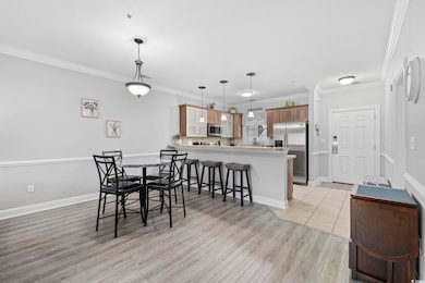 Dining area with ornamental molding and light wood