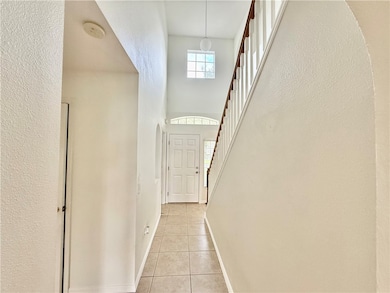 Doorway to outside featuring tile patterned flooring, a high ceiling, a textured wall, and stairs