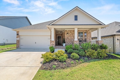 Craftsman house featuring brick siding, covered porch, concrete driveway, a garage, and a front yard