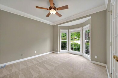 Carpeted space with a double door entry, plenty of natural light, a ceiling fan, and crown molding