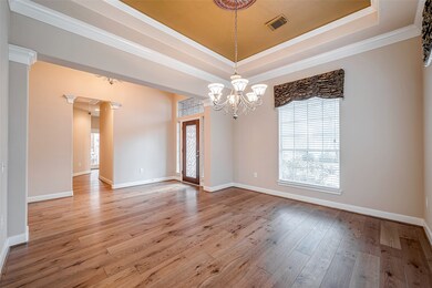 The formal dining area is just off of the entry, and features hardwood flooring, crown moulding, tiered ceiling, upgraded lighting with dimmer switch, and plenty of space for large furniture.