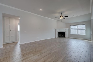 Unfurnished living room with vaulted ceiling, ornamental molding, and ceiling fan