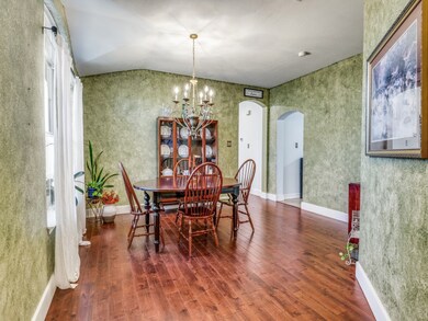 Dining room with a chandelier, arched walkways, wood finished floors, and vaulted ceiling