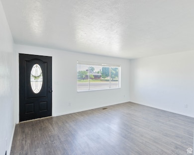 Entryway featuring wood finished floors, a textured ceiling, and baseboards