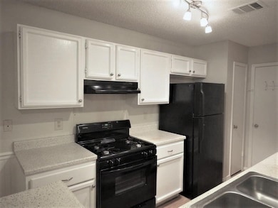 Kitchen featuring a textured ceiling, visible ven