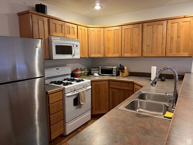 Kitchen with white appliances, brown cabinets, and dark countertops