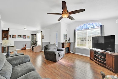 Living room featuring a ceiling fan, lofted ceiling, and light wood finished floors