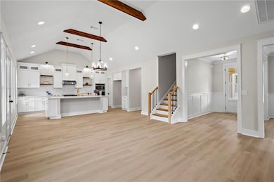 Unfurnished living room with light wood-style flooring, stairway, a chandelier, recessed lighting, and a wainscoted wall