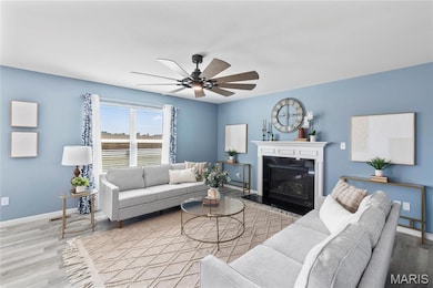 Living room featuring wood finished floors, a fireplace with flush hearth, and ceiling fan