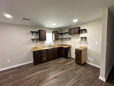 Kitchen with open shelves, dark brown cabinetry, dark wood-type flooring, light countertops, and recessed lighting