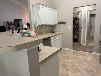 Kitchen with dishwasher, white cabinetry, light countertops, and baseboards